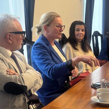Grupa czterech osób w strojach formalnych dyskutuje w konferencyjnym pomieszczeniu, podkreślając znaczenie doradztwa zawodowego i nowoczesnych metod nauczania. (wygenerowano przez AI)
