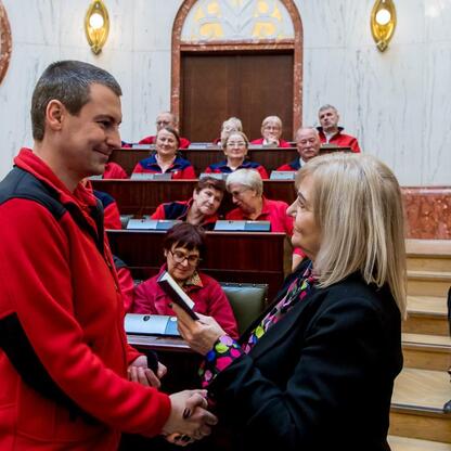 Formalna uroczystość w Sali Sejmu Śląskiego, gdzie przewodnicy turystyczni otrzymują wyróżnienia za swoje zasługi. (wygenerowano przez AI)