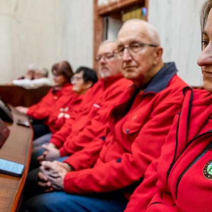 Zdjęcie przedstawia grupę przewodników turystycznych w czerwonych kurtkach uczestniczących w uroczystości z okazji Międzynarodowego Dnia Przewodników Turystycznych w Sali Sejmu Śląskiego. (wygenerowano przez AI)