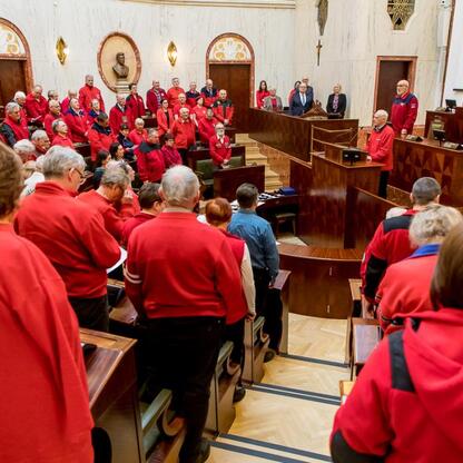 Formalne spotkanie w Sali Sejmu Śląskiego, gdzie grupa w czerwonych kurtkach słucha przemówienia. (wygenerowano przez AI)