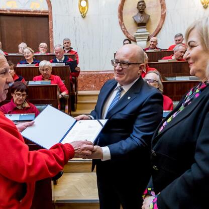 Formalna uroczystość w Sali Sejmu Śląskiego, gdzie przewodnicy turystyczni otrzymują wyróżnienia za swoje zasługi. (wygenerowano przez AI)