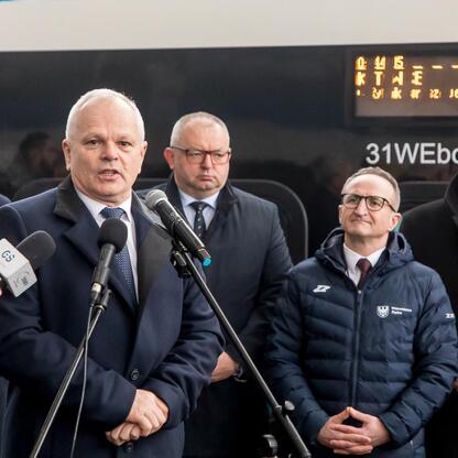 Grzegorz Boski i Wojciech Saługa prowadzą konferencję prasową na tle pociągu Impuls 2, zasiliącego tabor Kolei Śląskich. (wygenerowano przez AI)