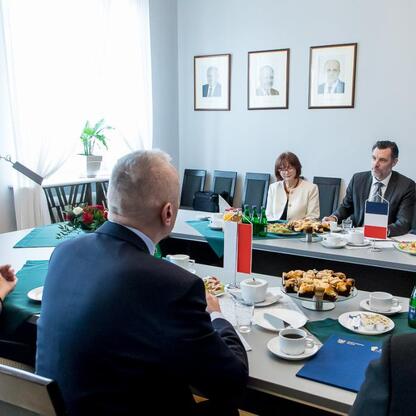 Formalne spotkanie w konferencyjnym pomieszczeniu, gdzie francuski konsul generalny Cédric Peltier omawia współpracę z Leszkiem Pietraszkiem i Anną Krasuską-Terrillon. (wygenerowano przez AI)