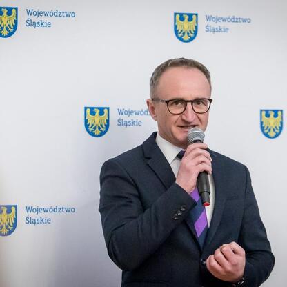 Wicemarszałek Województwa Śląskiego Grzegorz Boski przemawia na podium, prezentując projekty z funduszy EFRROW. (wygenerowano przez AI)