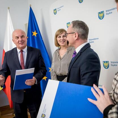 Fotografia przedstawia ceremonię wręczenia umów finansowych dla lokalnych projektów infrastrukturalnych w regionie Śląska. (wygenerowano przez AI)
