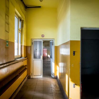 Korytarz w budynku przeznaczonym do przebudowy, z żółtymi ścianami i płytkami na podłodze, w ramach projektu transformacji byłego KWK Kazimierz-Juliusz w Sosnowcu. (wygenerowano przez AI)
