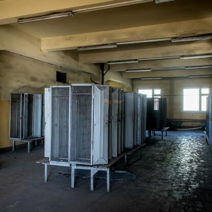 Abandoned industrial space, possibly former coal mine, with metal-framed lockers and tiled floor showing signs of age and decay. (wygenerowano przez AI)