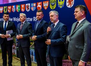 Mężczyzna w garniturze podpisuje dokument, podczas gdy druga osoba stoi za nim. Tło zaznacza Konwent Marszałków Małopolska 2023. (wygenerowano przez AI)