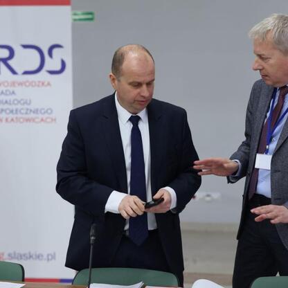 Grupa ludzi w Katowicach podczas briefingu prasowego Wojewódzkiej Rady Dialogu Społecznego, omawiając wpływy unijnej polityki klimatyczno-energetycznej na przemysł i gospodarkę. (wygenerowano przez AI)