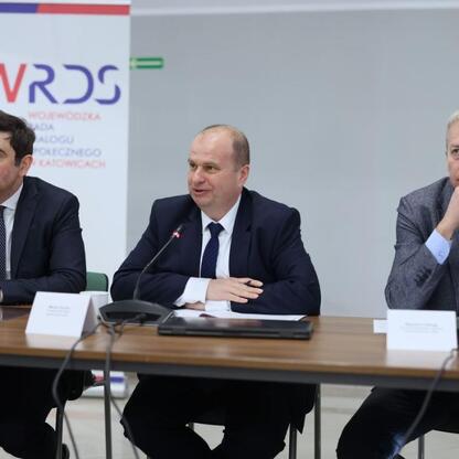 Trzech mężczyzn dyskutuje o polskim gospodarstwie i energetyce podczas briefingu prasowego Wojewódzkiej Rady Dialogu Społecznego w Katowicach. (wygenerowano przez AI)