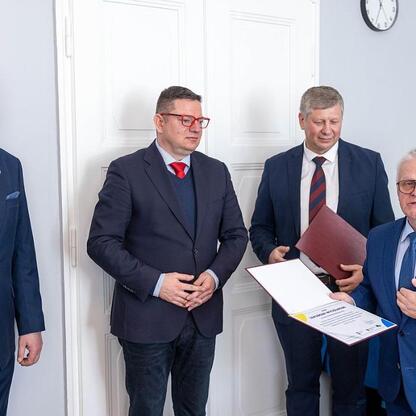 Czterech mężczyzn w garniturach uczestniczy w formalnym posiedzeniu Wojewódzkiej Rady Rynku Pracy. (wygenerowano przez AI)