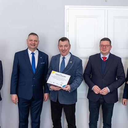 Grupa czterech mężczyzn w strojach formalnych, uczestniczących w uroczystości związanego z Wojewódzką Radą Rynku Pracy. (wygenerowano przez AI)