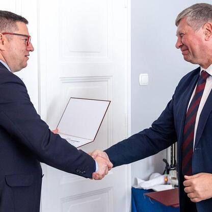Dwóch mężczyzn w strojach formalnych trzyma się za ręce w biurze, podczas obrad Wojewódzkiej Rady Rynku Pracy. (wygenerowano przez AI)