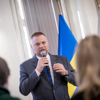 Rafał Adamczyk, członek Zarządu Województwa Śląskiego, przemawia na mikrofonie podczas finału konkursu wiedzy o pierwszej pomocy. (wygenerowano przez AI)