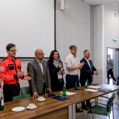 Zakończenie konkursu wiedzy o pierwszej pomocy, uczestnicy i władze gratulują i uśmiechają się. (wygenerowano przez AI)
