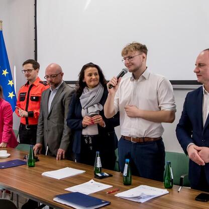 Grupa uczestników i oficjalnych z Młodzieżowego Sejmiku Województwa Śląskiego podczas finału konkursu wiedzy o pierwszej pomocy. (wygenerowano przez AI)