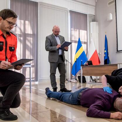 Paramedic P. Nowicki assesses a person during a first aid simulation at the Silesian Voivodeship first aid knowledge contest. (wygenerowano przez AI)