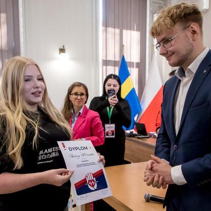Paulina Pilszak prezentuje dyplom na ceremonii wręczenia nagród w konkursie wiedzy o pierwszej pomocy dla młodzieży z województwa śląskiego. (wygenerowano przez AI)