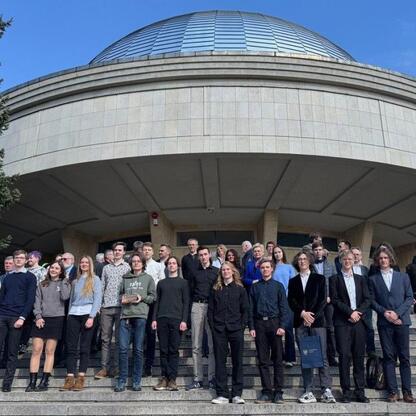 Grupa studentów z 68. Olimpiady Astronomicznej na schodach Planetarium w Śląskim Parku Nauki w Chorzowie. (wygenerowano przez AI)