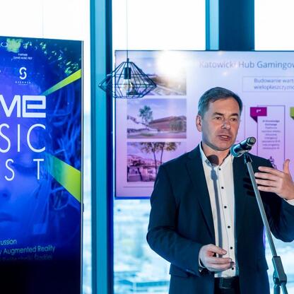 Na zdjęciu: Mężczyzna przemawia na konferencji prasowej Game Music Fest, festiwalu muzyki z gier komputerowych, w Katowicach. (wygenerowano przez AI)