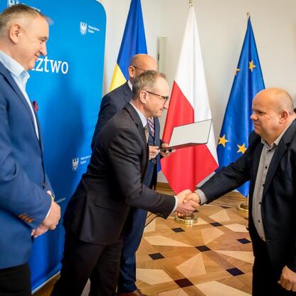 Wicemarszałek Grzegorz Boski wręcza listy gratulacyjne przedstawicielom ośmiu podmiotów otrzymujących wsparcie w inwestycjach w gospodarkę wodno-ściekową województwa śląskiego. (wygenerowano przez AI)