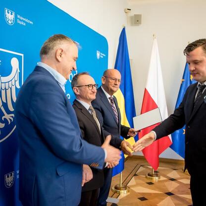 Wicemarszałek Grzegorz Boski wręcza listy gratulacyjne przedstawicielom otrzymania dofinansowania dla inwestycji w gospodarkę wodno-ściekową województwa śląskiego. (wygenerowano przez AI)