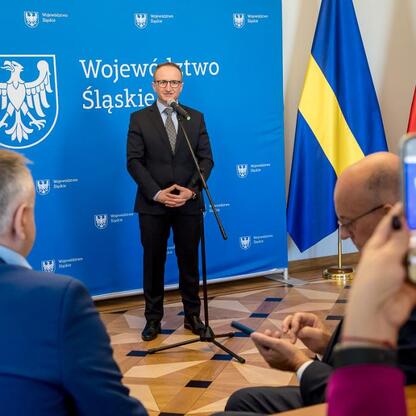 Wicemarszałek Grzegorz Boski przemawia w Sejmiku Śląskim, wręczając listy gratulacyjne za wsparcie w inwestycjach wodno-ściekowych. (wygenerowano przez AI)