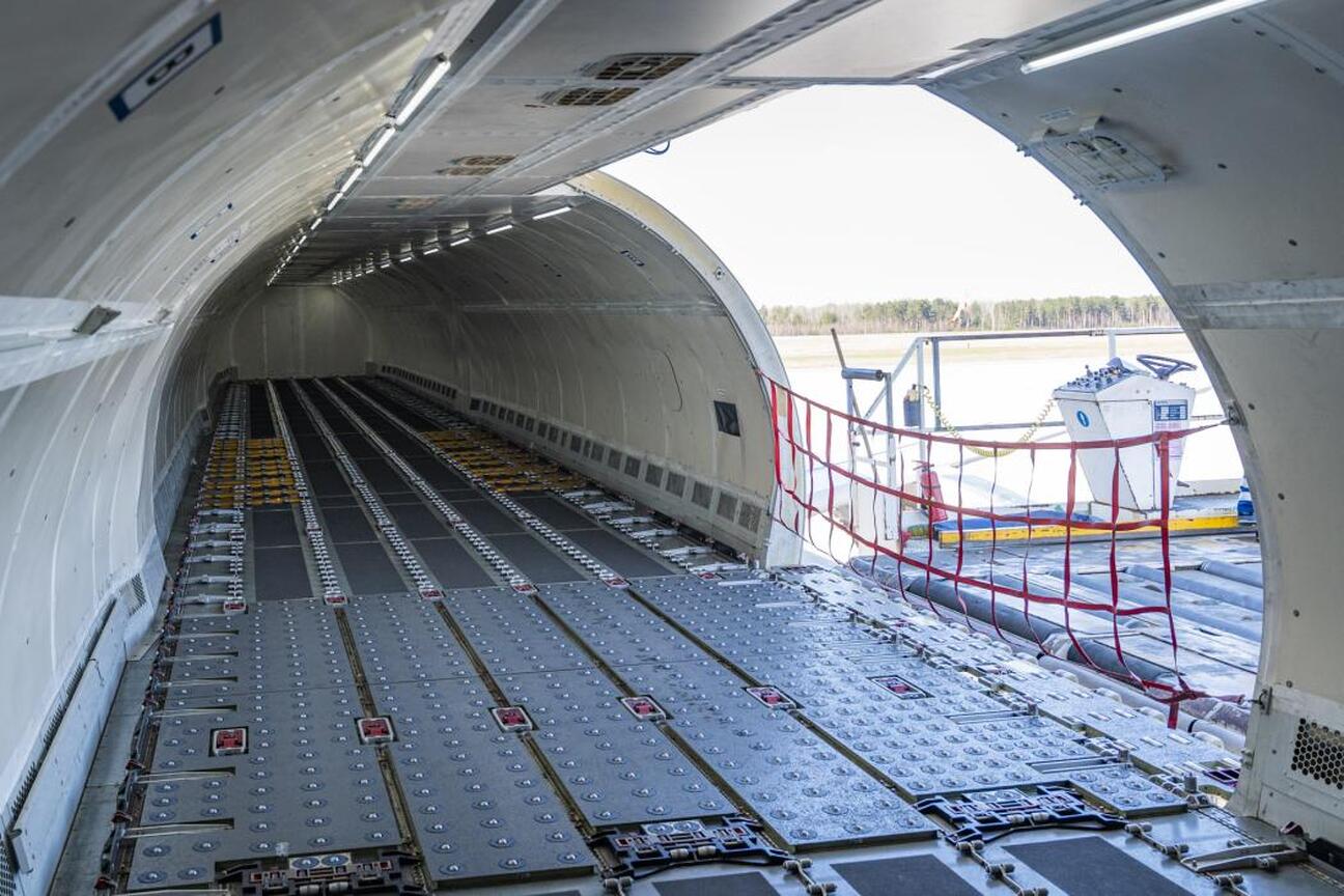 Wnętrze Airbusa A321F, przystosowane do przewozu 28 ton ładunku, z widocznymi metalowymi panelami podłogowymi i otwartymi drzwiami do ładunku. (wygenerowano przez AI)