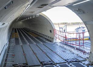 Wnętrze Airbusa A321F, przystosowane do przewozu 28 ton ładunku, z widocznymi metalowymi panelami podłogowymi i otwartymi drzwiami do ładunku. (wygenerowano przez AI)