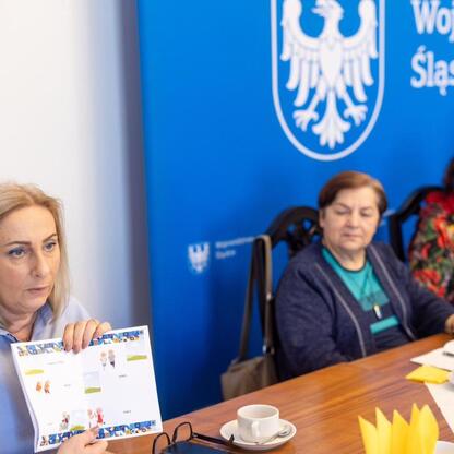 Zebrała się grupa seniorów w sali Sejmu Śląskiego, omawiając plany uroczystości związanych z 50-leciem Uniwersytetu Trzeciego Wieku. (wygenerowano przez AI)