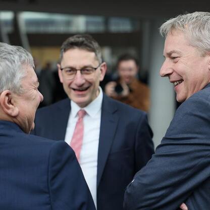 Trzech mężczyzn w garniturach omawiających w Mediatece w Warszawie. (wygenerowano przez AI)