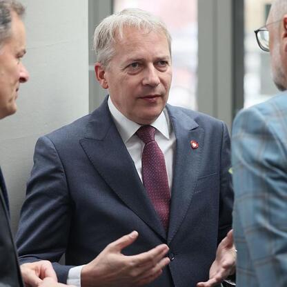 Trzech mężczyzn w formalnym stroju rozmawiających, prawdopodobnie na konferencji energetycznej w Mediatece w Tychach. (wygenerowano przez AI)