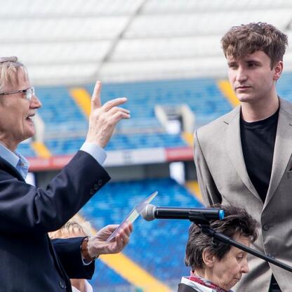 II Sesja Rady Młodzieżowej na Stadionie Śląskim, gdzie mówca w garniturze gestykuluje,激励着年轻人群体。 (wygenerowano przez AI)