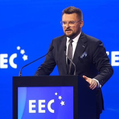 Mężczyzna w ciemnym garniturze przemawia na podium podczas XVII Europejskiego Kongresu Gospodarczego w Katowicach. (wygenerowano przez AI)