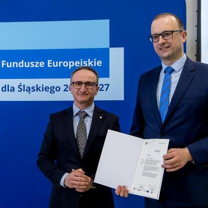 Wicemarszałek Grzegorz Boski wręcza dokumenty podczas uroczystości Funduszy Europejskich dla Śląska 2021-2027. (wygenerowano przez AI)