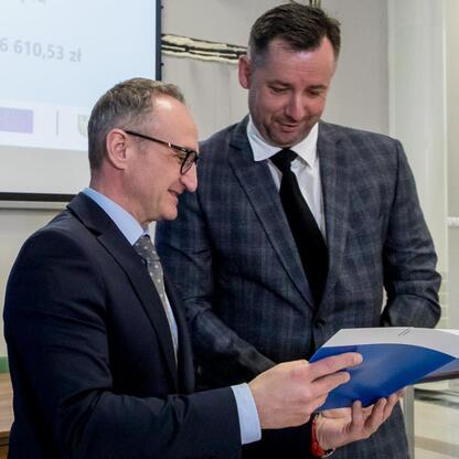 Wicemarszałek Województwa Śląskiego Grzegorz Boski i jego współpracownik omawiają dokumenty związane z projektem dotyczącym funduszy europejskich. (wygenerowano przez AI)