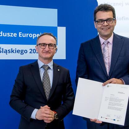 Grzegorz Boski, wicemarszałek Województwa Śląskiego, wręcza listy gratulacyjne beneficjentom projektów dofinansowanych z Europejskich Funduszy dla Śląska 2021-2027. (wygenerowano przez AI)