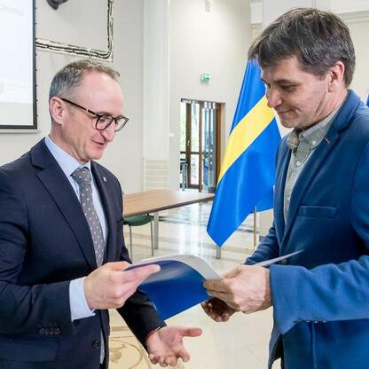 Wicemarszałek Województwa Śląskiego Grzegorz Boski wręcza beneficjentom listy gratulacyjne w ramach projektów unijnych. (wygenerowano przez AI)
