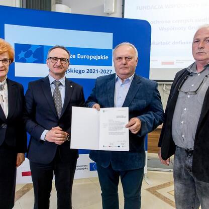 Wicemarszałek Grzegorz Boski wręcza beneficjentom listy gratulacyjne za projekty dofinansowane z Europejskiego Funduszu Rozwoju Regionalnego dla Śląska 2021-2027. (wygenerowano przez AI)