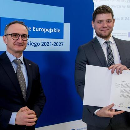 Wicemarszałek Województwa Śląskiego Grzegorz Boski wręcza beneficjentom listy gratulacyjne za sukcesy w projekcie Funduszy Europejskich dla Śląska 2021-2027. (wygenerowano przez AI)
