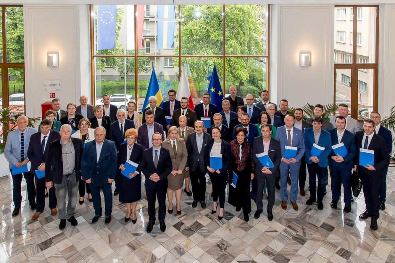 Grzegorz Boski, wicemarszałek Województwa Śląskiego, wręcza dokument przed prezentacją o funduszach europejskich dla Śląska 2021-2027. (wygenerowano przez AI)