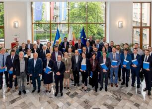Grzegorz Boski, wicemarszałek Województwa Śląskiego, wręcza dokument przed prezentacją o funduszach europejskich dla Śląska 2021-2027. (wygenerowano przez AI)