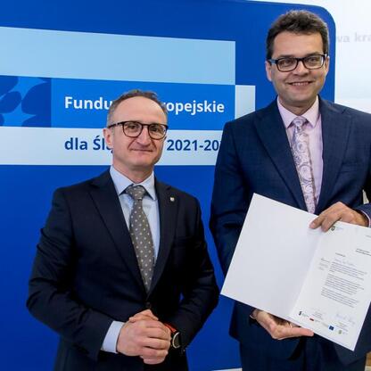 Wicemarszałek Województwa Śląskiego Grzegorz Boski wręcza listy gratulacyjne beneficjentom projektów dofinansowanych z Europejskich Funduszy dla Śląska 2021-2027. (wygenerowano przez AI)