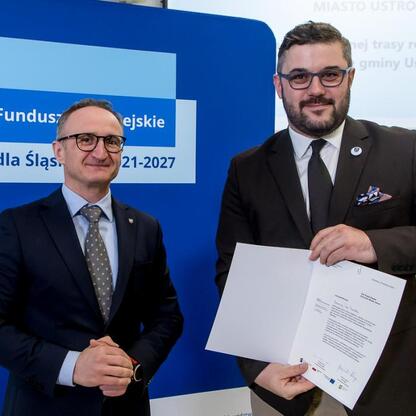 Wicemarszałek Województwa Śląskiego Grzegorz Boski wręcza dokumenty z funduszy Europejskiego Regionalnego Rozwoju dla Śląska 2021-2027. (wygenerowano przez AI)