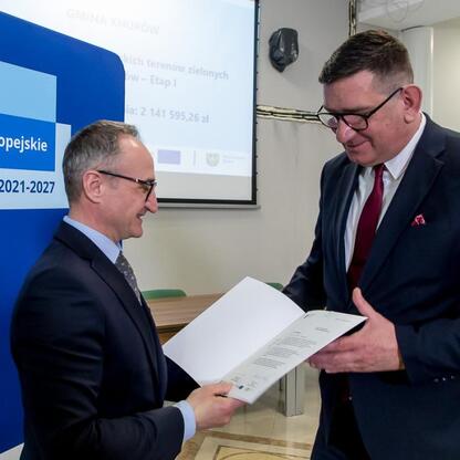 Grzegorz Boski, wicemarszałek Województwa Śląskiego, wręcza dokument przed prezentacją o funduszach europejskich dla Śląska 2021-2027. (wygenerowano przez AI)