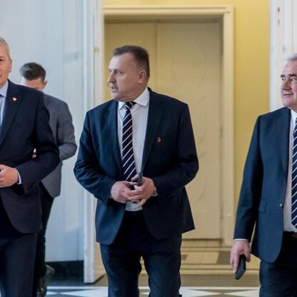 Trzech mężczyzn w garniturach i krawatach, uczestnicy uroczystości jubileuszowych Śląskiego Związku Piłki Nożnej. (wygenerowano przez AI)