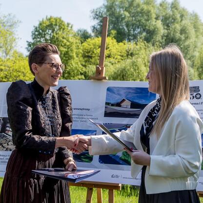 Dwie kobiety trzymają się za ręce przed tablicą informacyjną w Muzeum 