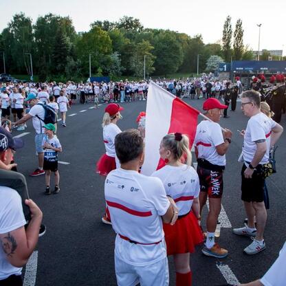 Bieg dla Flagi 2025 w Parku Śląskim, uczestnicy w białych koszulkach z czerwono-białymi pasami, festyn z orkiestrą i flagą Polski. (wygenerowano przez AI)