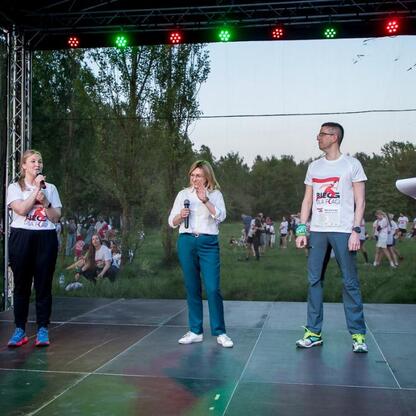 Na Biegu dla Flagi 2025 w Parku Śląskim, Joanna Bojczuk przemawia, a Paweł Bilangowski obsługuje imprezę. (wygenerowano przez AI)