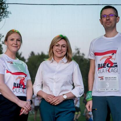 Grupa biegaczy w białych koszulkach uczestniczy w 